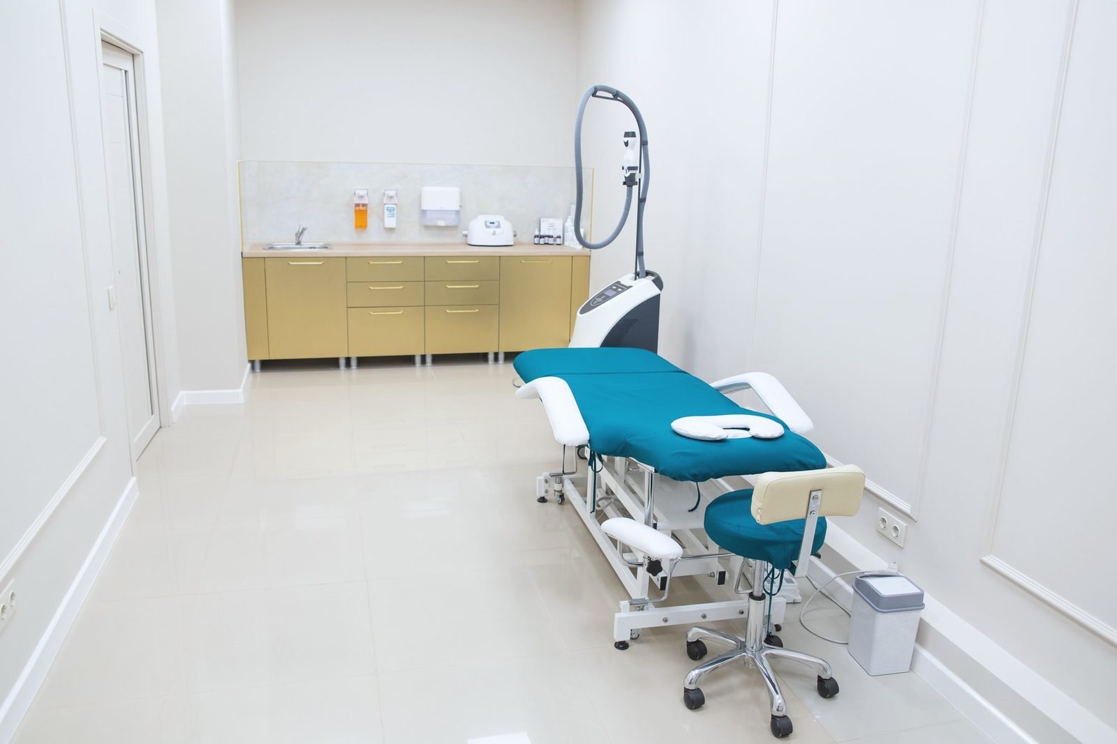 A treatment room with a counter, a sink and an adjustable table